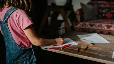 Getty Images A little girl with brown hair draws on a piece of paper