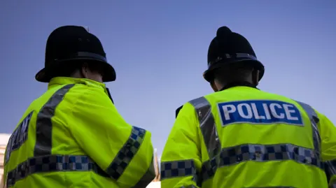 Getty Images Two police officers in high vis jackets and helmets facing away from the camera