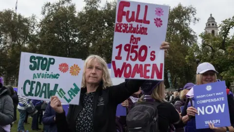 Getty Images A woman at the protest holds two signs. One reading 