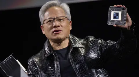 Getty Images Jensen Huang, co-founder and chief executive officer of Nvidia, speaks while holding the company's new GeForce RTX 50 series graphics cards and a Thor Blackwell robotics processor during the 2025 CES event in Las Vegas, Nevada, US.