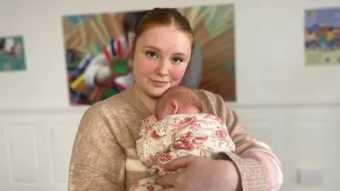 Young woman carrying a baby