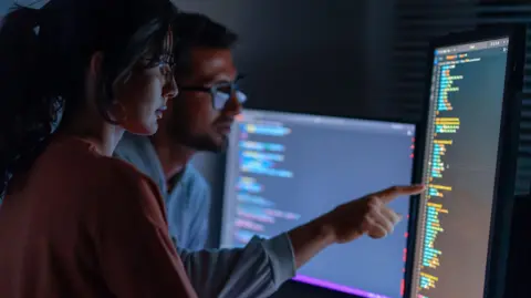 Getty Images Two coders look at a screen