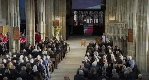 Rows of people sitting down in Hull Minster at the funeral. The photo is taken looking towards the front of the minster