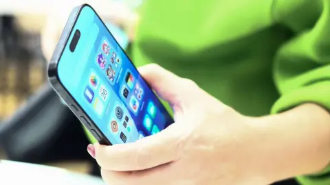 Getty Images Close-up of Apple iPhone 16 held in a person's hand. The person has a green top on.