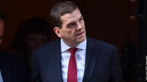 Getty Images Oliver Robbins looks away from photographers as he exits 10 Downing Street wearing a suit during his time as Brexit negotiator in 2019