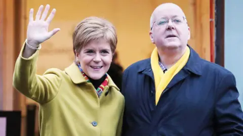 PA Media Nicola Sturgeon and Peter Murrell standing side by side in overcoats.