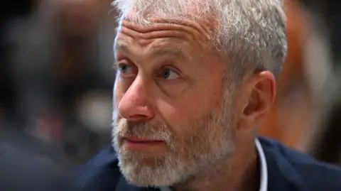 Getty Images A close of up a bearded Roman Abramovich in a blue suit and white shirt looking to his right