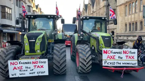 BBC/Malcolm Prior Two tractors with union flags attached to their cabs, and displaying signs reading No Farmers, No Food are pictured side-by-side in Oxford