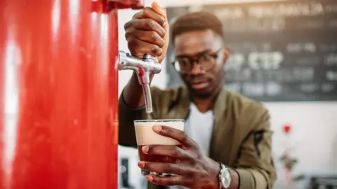 Getty Images A man pouring a glass of beer from a red keg