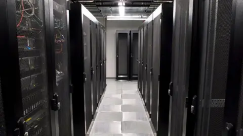 Getty Images Narrow corridor in data centres with racks of computer servers behind smoked glass on either side