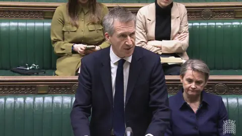 PA Media Dan Jarvis wearing a suit while speaking in the House of Commons. He is standing at the despatch box and Yvette Cooper is sitting behind him on the green front bench.