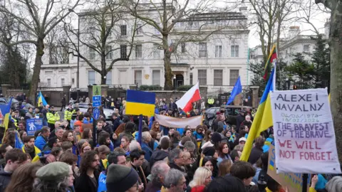 PA Media A group of protesters - holding Ukraine flags and a poster reading 