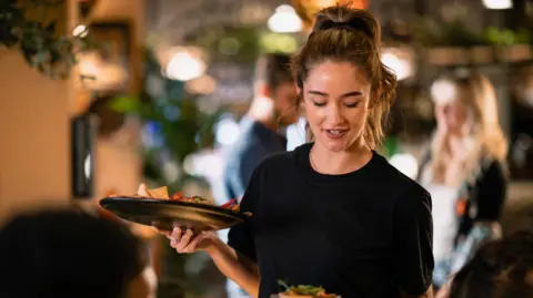 Getty Images Woman waiter serving in a restaurant