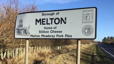 A white road sign with black lettering saying 