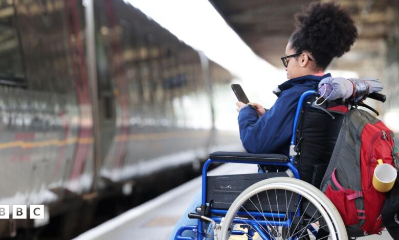 A woman in a wheelchair waiting to board a train, whilst using her phone.