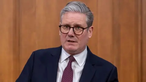 EPA Sir Keir Starmer stands in front of a wood panelled wall during a London news conference