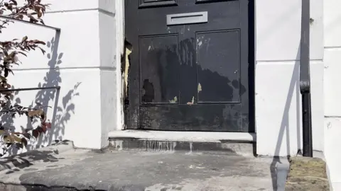 Fire damage on a black door, set in a white building