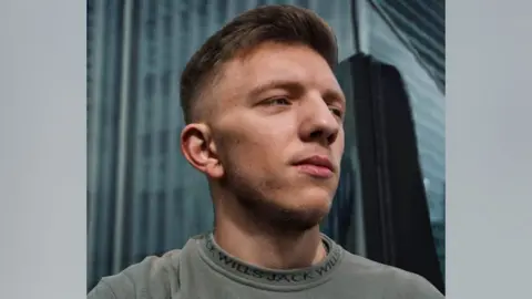 A man looking off to the right, wearing a grey jumper
