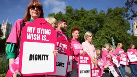 EPA Campaigners in favour of assisted dying outside Parliament, wearing pink and holding placards reading: