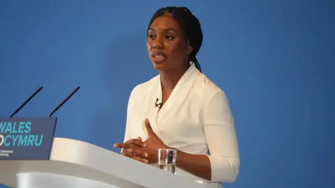 BBC Kemi Badenoch speaking at Welsh Conservative conference in Llangollen, in front of a podium that says #FIXWALES in Welsh and English.
