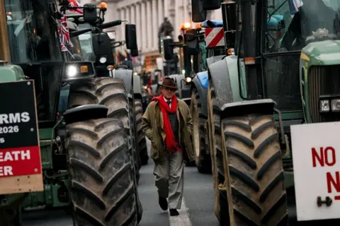 Getty Images Press officer for Reform UK Gawain Towler walks among tractors parked along Whitehall during a stop