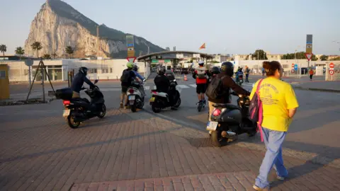 Reuters People on foot and motorbikes cross the border from Spain to Gibraltar at dawn, in front of the Rock
