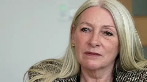 Qays Najim/BBC Kay Mason Billig is looking at the camera. We can see she's wearing a patterned suit jacket.