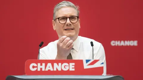Getty Images Sir Keir Starmer smiling in front of a podium with the word 