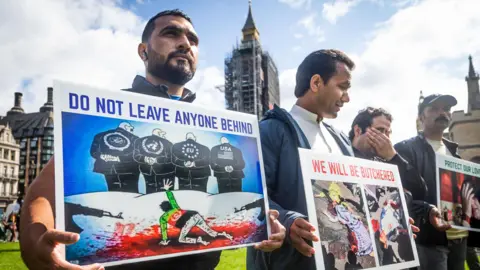 Getty Images Protesters in London hold placards calling for the safe evacuation of Afghans that had worked with the British military. The posters read: 