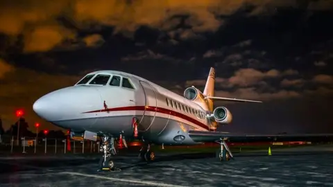 Getty Images Falcon 900B business jet standing on the tarmac at an airport at night