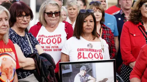 PA Media A group of family members protesting in May 2024 outside parliament. They are holding a photograph of their loved one and wearing white t-shirts saying