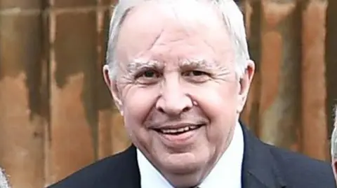 Charles McQuillan/Getty Images Lord Murphy of Torfaen pictured in 2018 at an event to celebrate the 20th anniversary of the Good Friday Agreement. He has short white hair and is smiling. He is wearing a black suit and white shirt.
