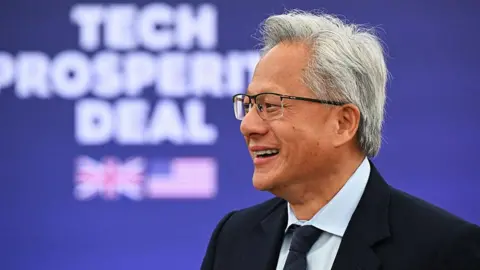 Getty Images Nvidia CEO Jensen Huang at a Business event hosted by US President Donald Trump and Britain's Prime Minister Keir Starmer. He is smiling and wearing a suit with a tie. He has grey hair and wears glasses.