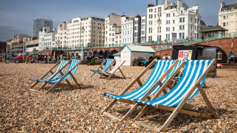 Getty Images Blue and white striped deck chairs sit on the pebbles on the seafront in Brighton city centre.